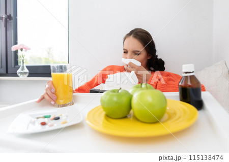 A teenager sitting on the bed snot his nose before taking the next dose of tablet medicine. A teenager sitting on the bed snot his nose before taking the next dose of tablet medicine. 115138474