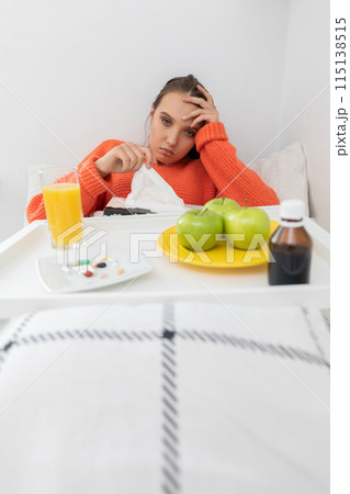 A young teenager lies on a bed and takes out handkerchiefs to blow her nose. A young teenager lies on a bed and takes out handkerchiefs to blow her nose. 115138515
