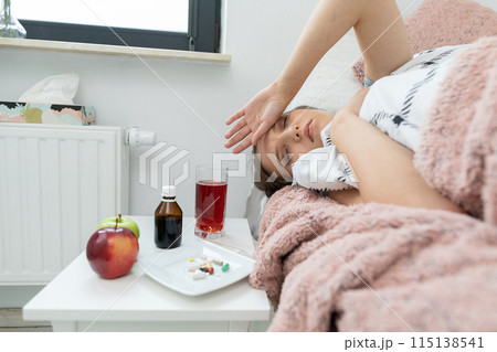A terrible headache. A sick teenager lies in her bed and three behind her head. A terrible headache. A sick teenager lies in her bed and three behind her head. 115138541