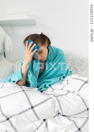 The teenager puts cold compresses on her head to reduce the high temperature. The teenager puts cold compresses on her head to reduce the high temperature. 115138654