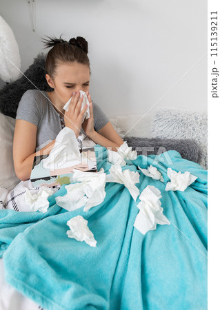 A cold teenager snot tears his nose in a handkerchief all the time under a warm duvet. 115139211