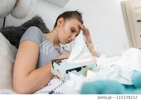 A young teenager lies in her bed because she is sick and has a chronic headache. 115139212