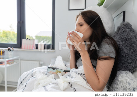 Very sick teenager lies in bed and groats in a handkerchief. 115139232