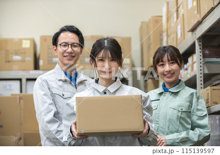 段ボールを持つ作業着姿の女性と男女の作業員 115139597
