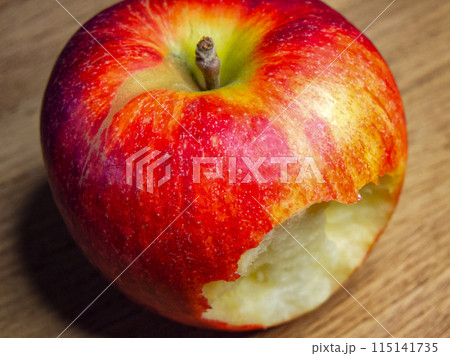 Freshly Bitten Apple. A red apple with a bite taken out, resting on a wooden surface, evoking themes of health and freshness. Freshly Bitten Apple. A red apple with a bite taken out, resting on a wooden surface, evoking themes of health and freshness. 115141735