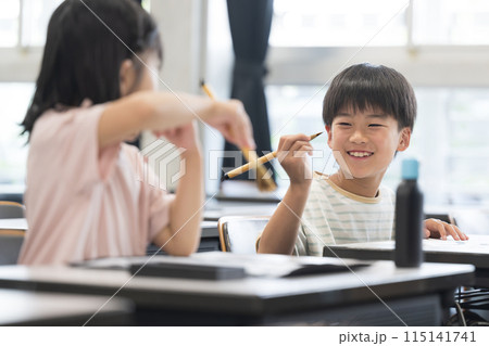 明るい小学校の教室で習字を教わる小学生の女の子と男の子 楽しいイメージ 明るい小学校の教室で習字を教わる小学生の女の子と男の子 楽しいイメージ 115141741
