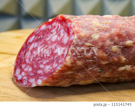 Salami with visible fat marbling, suggesting a gourmet or deli setting, ready to be sliced. 115141745