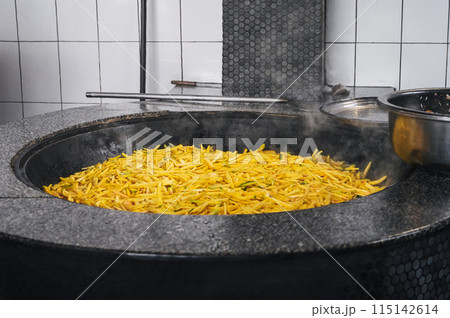 yellow carrots are stewed in cauldron for cooking Asian Uzbek pilaf in kitchen in Tashkent in Uzbekistan 115142614