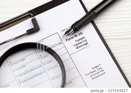 IRS Form W-2G Certain Gambling Winning blank on A4 tablet lies on office table with pen and magnifying glass close up IRS Form W-2G Certain Gambling Winning blank on A4 tablet lies on office table with pen and magnifying glass close up 115143827