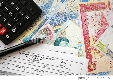 Iranian annual income tax return form F20-25-006 ready to fill on table with pen, calculator and iranian money close up Iranian annual income tax return form F20-25-006 ready to fill on table with pen, calculator and iranian money close up 115143889