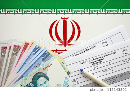 Iranian annual income tax return form F20-25-006 ready to fill on table with pen and iranian money on flag close up 115143892
