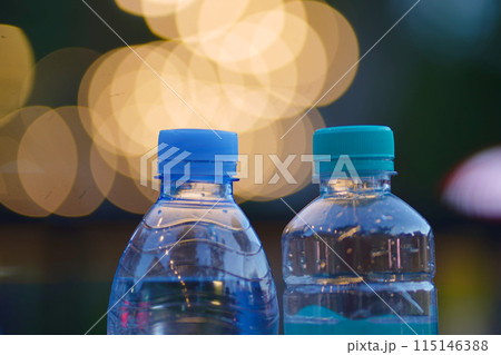 Two clear plastic water bottles with blue caps 115146388