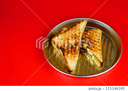 a golden brown grilled cheese sandwich on a rectangular metal plate. 115146395