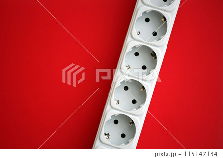 White electrical multi plug extender with european socket on bright red background close up 115147134