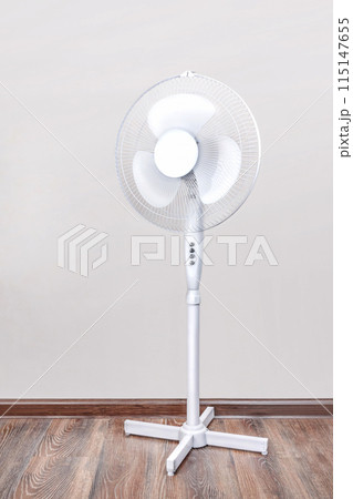An electric fan is on the floor. Relief Help from the heat, hot summer. Close up vertical photo An electric fan is on the floor. Relief Help from the heat, hot summer. Close up vertical photo 115147655
