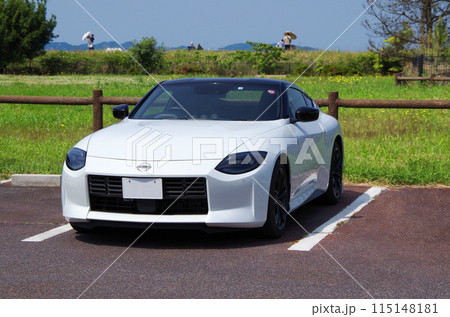 快晴の休日に白色の国産スポーツカーでドライブに出掛けて公園の駐車場で休憩して景色を眺めているイメージ 115148181