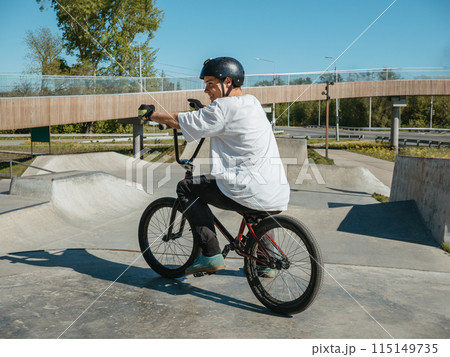 Young BMX bicycle rider smiling, posing in skatepark Young BMX bicycle rider smiling, posing in skatepark 115149735