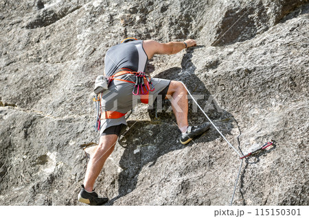 Close up of a climber with equipment on a belt, climbing a rock wall Close up of a climber with equipment on a belt, climbing a rock wall 115150301