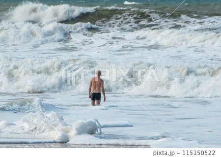 A man alone swims in the Atlantic Ocean in a storm, big waves, danger on the beach 115150522