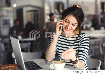 Woman working remotely from coffee shop. Cappucino and laptop on table. Female freelancer working on notebook in cafe. 115150753