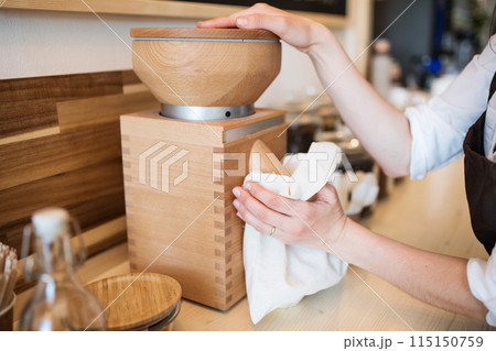Shop assistant milling flour in package-free store using reusable containers. Zero waste shops offering package-free bulk goods and sustainable alternatives. 115150759