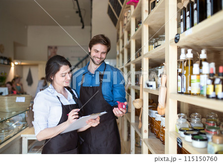 Two shop assistants in package-free store using reusable containers, checking inventory. Zero waste shops offering package-free bulk goods and sustainable alternatives. Two shop assistants in package-free store using reusable containers, checking inventory. Zero waste shops offering package-free bulk goods and sustainable alternatives. 115150760
