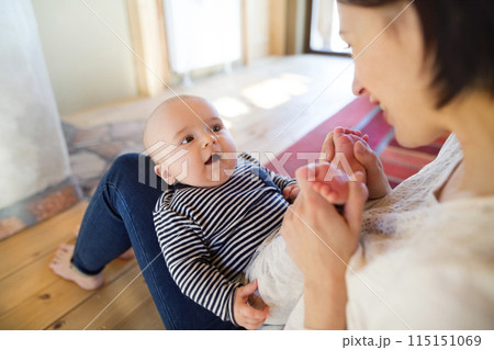 Mother playing with small baby, holding him on her knees. Unconditional paternal love, mother's Day concept. 115151069