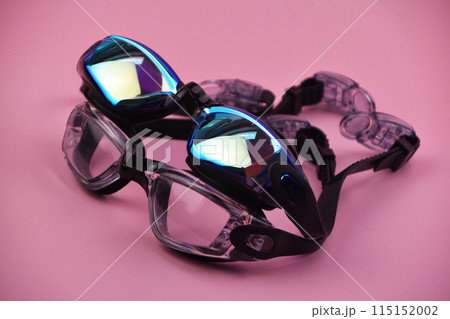 Swimming goggles resting against a vibrant pink background, offering a striking and colorful contrast. Swimming goggles resting against a vibrant pink background, offering a striking and colorful contrast. 115152002