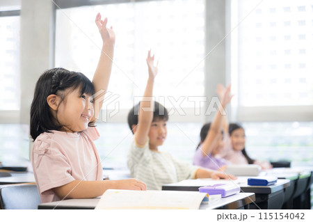 授業をうけ勉強する元気な小学生 ハイと手を挙げ挙手をする 115154042
