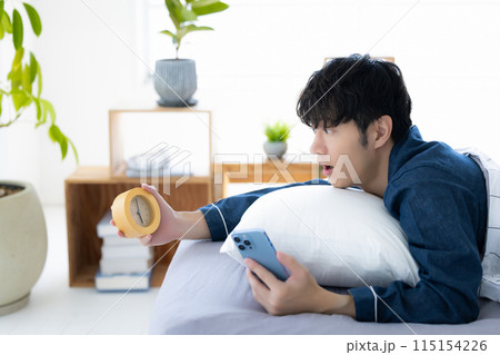寝坊して時計を見ている男性 115154226