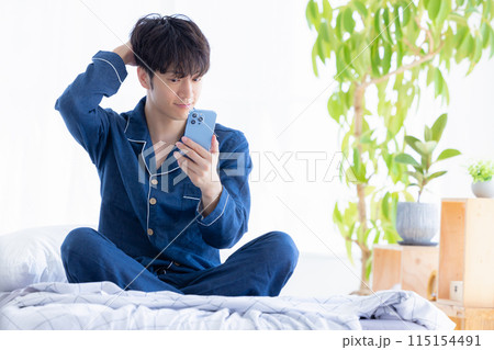 朝起きてスマホを見ている男性 115154491