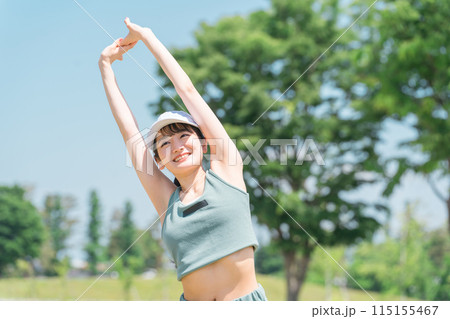 公園でストレッチ・準備体操・ウォーミングアップ・深呼吸するスポーツウェア姿の若いアジア人女性 115155467