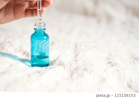 Females hand holding face serum dropper. Females hand holding face serum dropper. 115156153