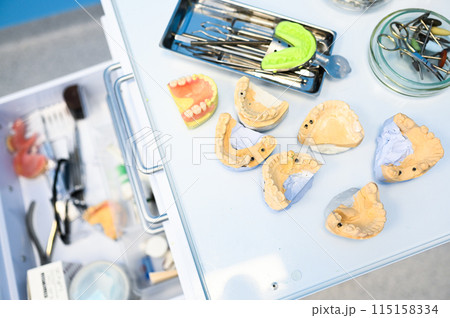 Different professional dental equipment, instruments and tools in a dentists stomatology office clinic on a white background. Silicone cast of the jaw. 115158334