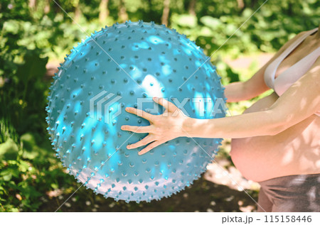 Beautiful young pregnant woman doing yoga exercising with fitness pilates ball in park outdoor. Standing and holding with both hands. Active future mother sport lifestyle. Healthy pregnancy concept Beautiful young pregnant woman doing yoga exercising with fitness pilates ball in park outdoor. Standing and holding with both hands. Active future mother sport lifestyle. Healthy pregnancy concept 115158446