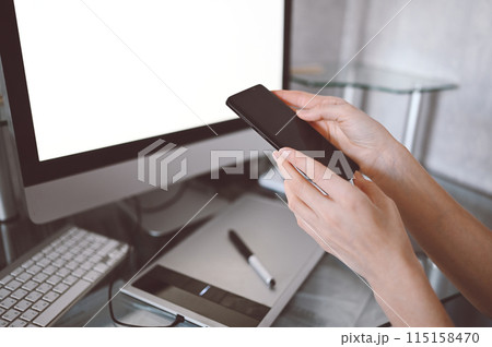 Female hands using smart phone in interior workplace, freelance business woman using cell phone at office desk, working from home using smart phone and notebook computer. 115158470