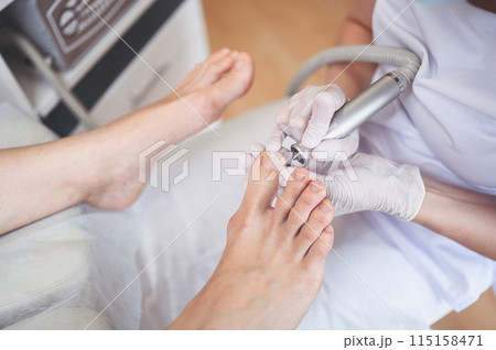 Hardware medical pedicure with nail file drill apparatus. Patient on pedicure treatment with pediatrician chiropodist. Foot peeling treatment at spa with a special device. Clinic of Podiatry Podology 115158471