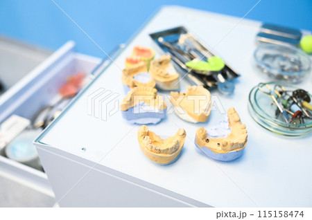 Different professional dental equipment, instruments and tools in a dentists stomatology office clinic on a white background. Silicone cast of the jaw. 115158474