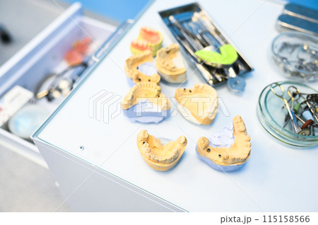 Different professional dental equipment, instruments and tools in a dentists stomatology office clinic on a white background. Silicone cast of the jaw. 115158566