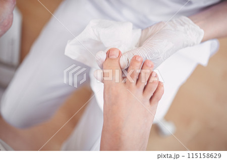 Pedicurist doing professional medical pedicure procedure in beauty salon with special eguipment. Foot treatment in SPA salon. Podiatry clinic. Beautician doctor hands in white gloves with female legs 115158629