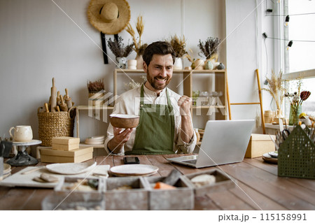 Caucasian man potter happy with online sale of bowl on Internet. Caucasian man potter happy with online sale of bowl on Internet. 115158991