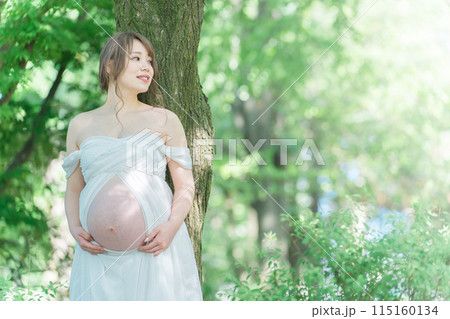 マタニティフォトの撮影をするアジア人妊婦の女性（木漏れ日） 115160134