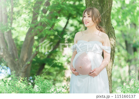 マタニティフォトの撮影をするアジア人妊婦の女性（木漏れ日） 115160137