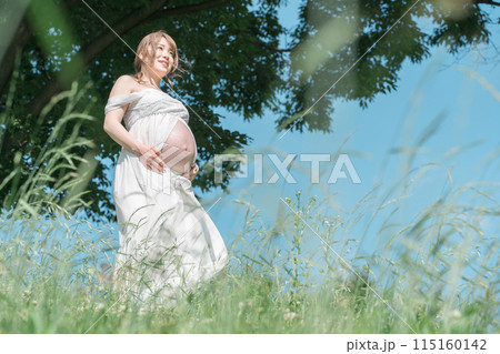マタニティフォトの撮影をするアジア人妊婦の女性（青空・森・森林） 115160142