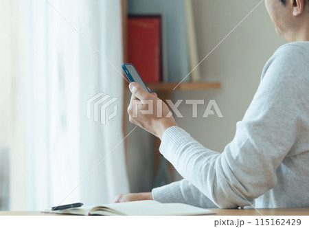 スマホと手帳をチェックするミドル男性 115162429
