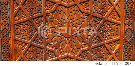 Arabic Uzbek Islamic patterns arabesque ornament on brown wooden carved door in Uzbekistan close up 115163092