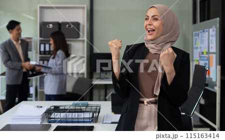 Successful business woman using laptop computer and smartphone in office. Happy woman, entrepreneur, small business owner working online. 115163414