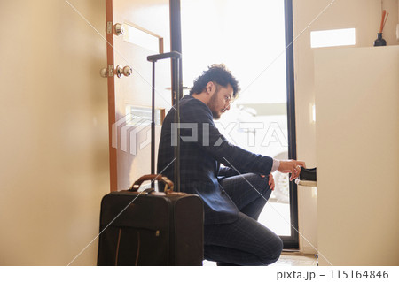 下駄箱で旅行の準備をする男性 下駄箱で旅行の準備をする男性 115164846
