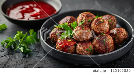 Four Grilled Meatballs With Parsley and Red Sauce on Black Plate 115165826