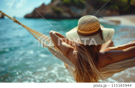 Woman Relaxing in a Hammock on a Beach With Blue Ocean in the Background 115165944